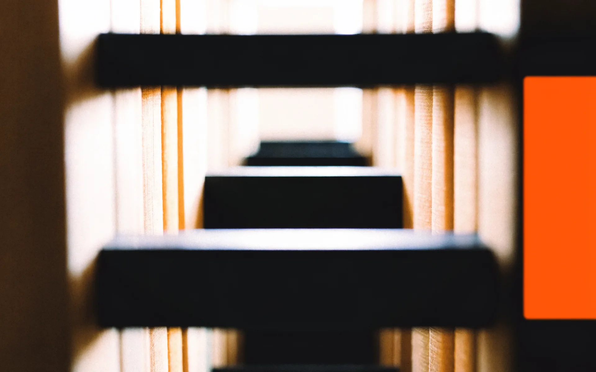 Abstract view through dark library shelving and warm book-cloth volumes.